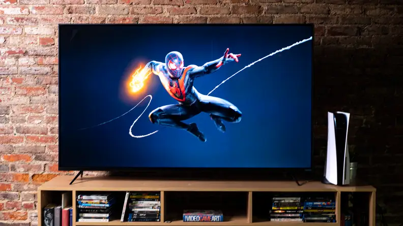 A TV in front of a brick background connected to a PlayStation 5 with the splash screen for Spider-Man: Miles Morales
