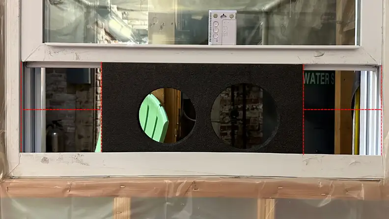 A close-up of the vent board installed in a standard window. Dotted red lines showcase the over 10 inches of space left on either side.