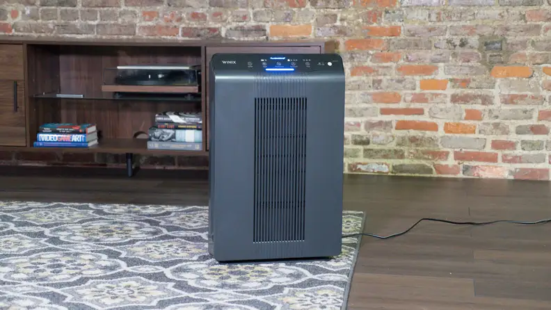 An air purifier stands on a carpet