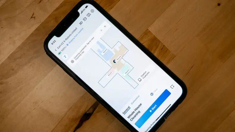 iPhone on wooden countertop displaying Ecovacs Home App.
