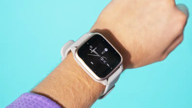 A close-up of a person's arm with a Garmin Venu Sq 2 fitness tracker on their wrist.