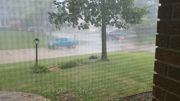 Automower 450XH EPOS robot lawn mower moving across lawn on an extremely windy and rainy day.