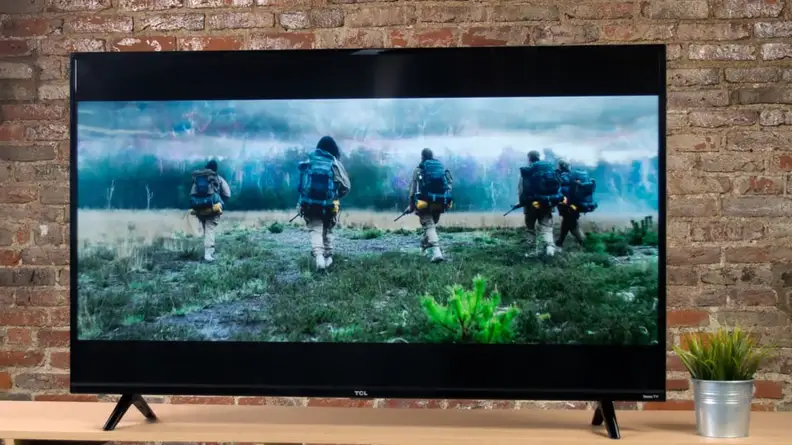 A TV showing a drama against a brick wall.