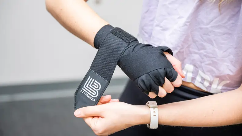A woman wrapping her hands with the Liteboxer hand wraps.