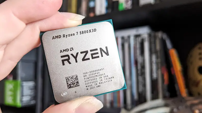 A close up of a desktop processor being held between someone's fingers
