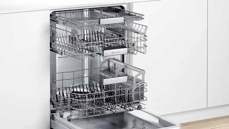 A close-up of the Bosch SHE88PZ65N 800 Series dishwasher installed in a modern kitchen. Its door is open and its racks have been pulled out slightly, so you can see all of the dishes stored inside.
