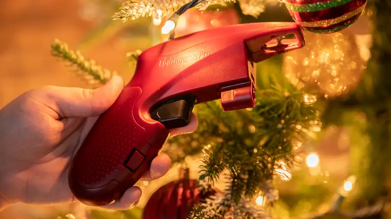 Red glue-gun-shaped gadget next to glowing christmas tree lights