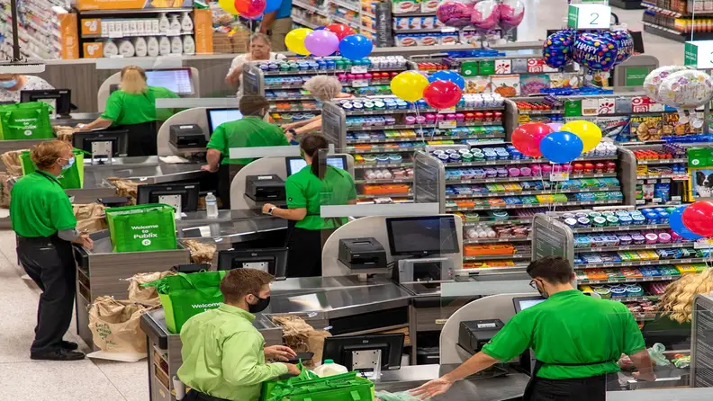 Publix cashiers working checkout lanes with birthday balloons overhead