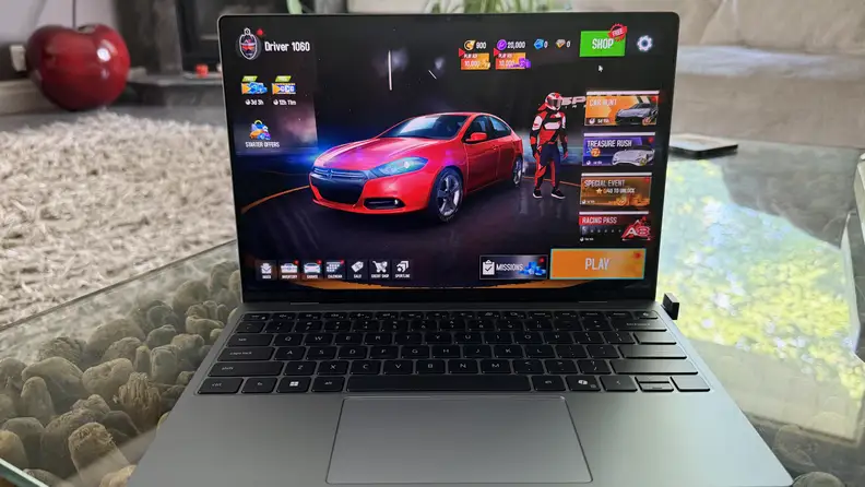 Dell XPS 13 sitting on a glass table with the screen displaying a red car.