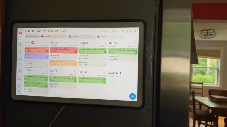A digital calendar hangs on a refrigerator
