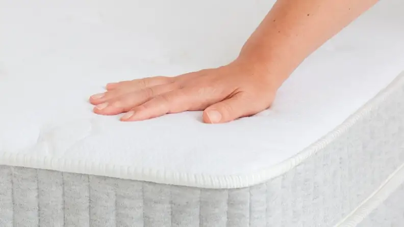 a hand presses into the surface of the Allswell Supreme mattress