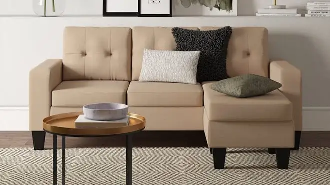 Nude couch against white wall on a patterned carpet