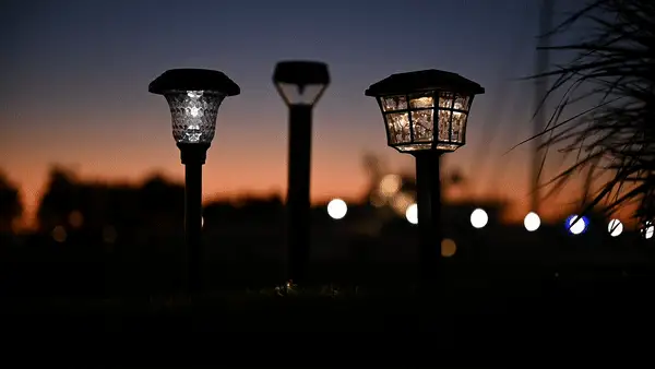 Three outdoor solar lights appear in a dark outdoor scene—the center light flicks on and off.