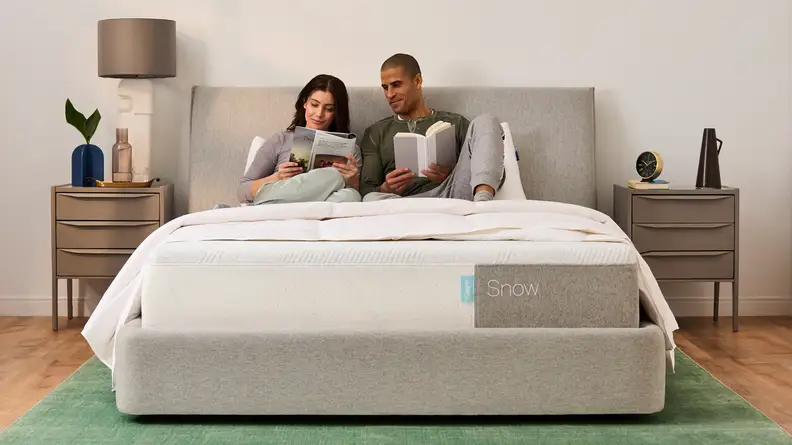 A couple lying under the covers on the Casper Snow mattress