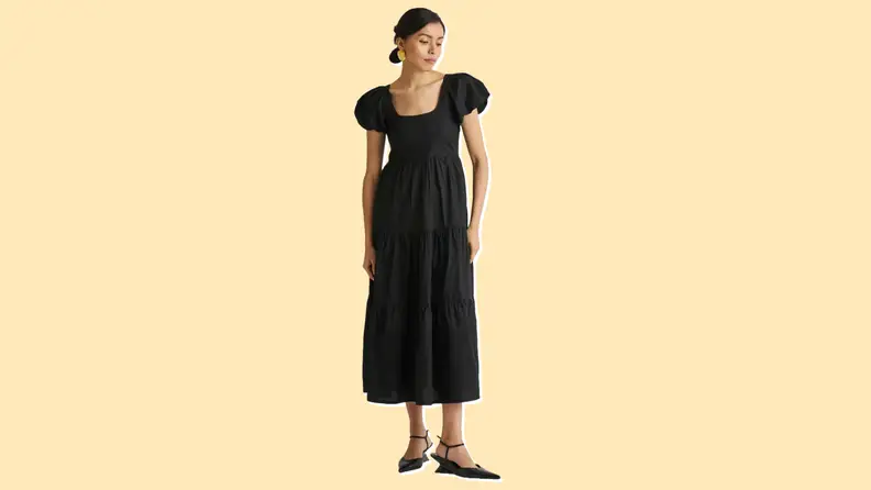 Photo of a woman wearing the Reistor Puff Sleeve Tiered Dress in black.