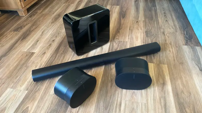 Two Sonos Era 300 speakers alongside a Arc soundbar and Sub (3rd Gen) sitting on a wooden floor.
