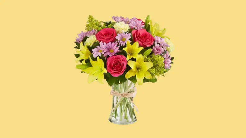 Vase of multi-colored flowers against yellow background