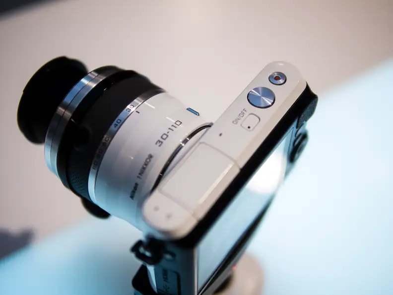 The top controls on the Nikon 1 S2 are limited to a shutter release, power button, and record button.