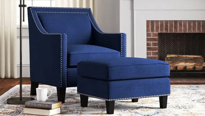 Blue tufted armchair with ottoman in living room.