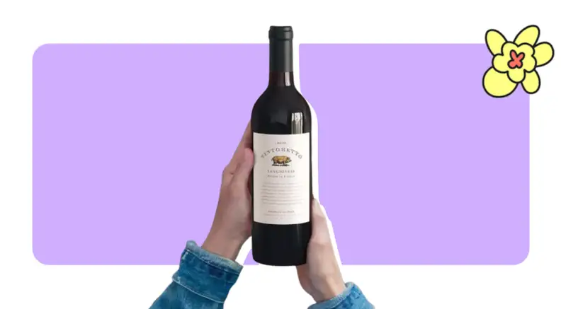 Two hands holding a bottle of a bottle of red wine in front of purple background with a yellow flower in the corner.