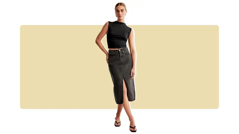 A model wearing a black midi-length denim skirt with a black tank top.