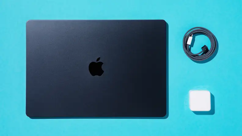 MacBook Air 15 M2 closed next to lightning cord and charger block.