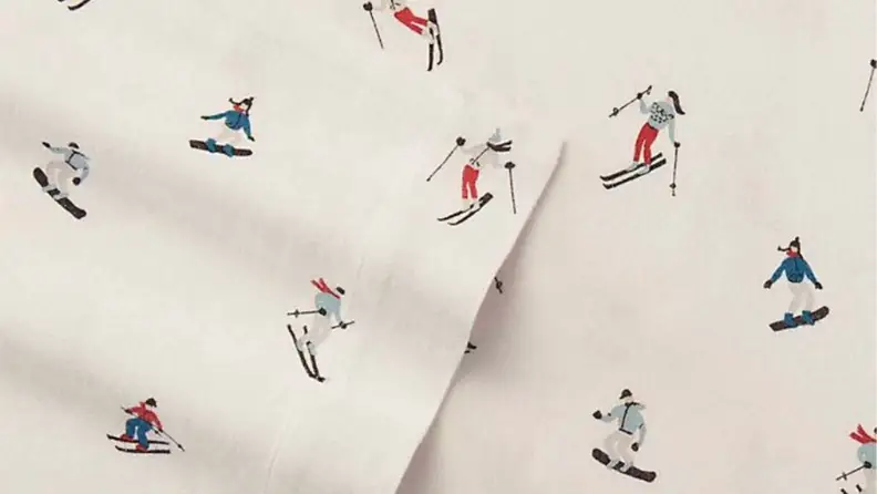 a close-up photo of Eddie Bauer flannel sheets with a cream background and skiers