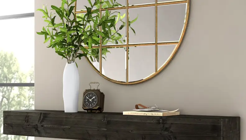 Round gold mirror above hallway table with plant on it