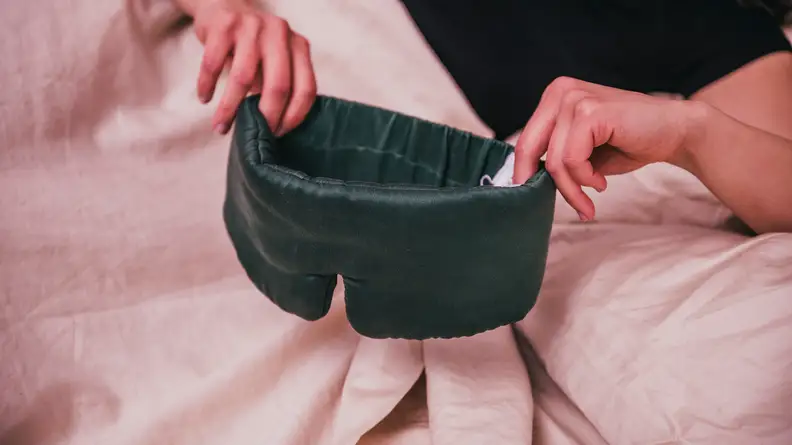 Person holds eye mask in bed