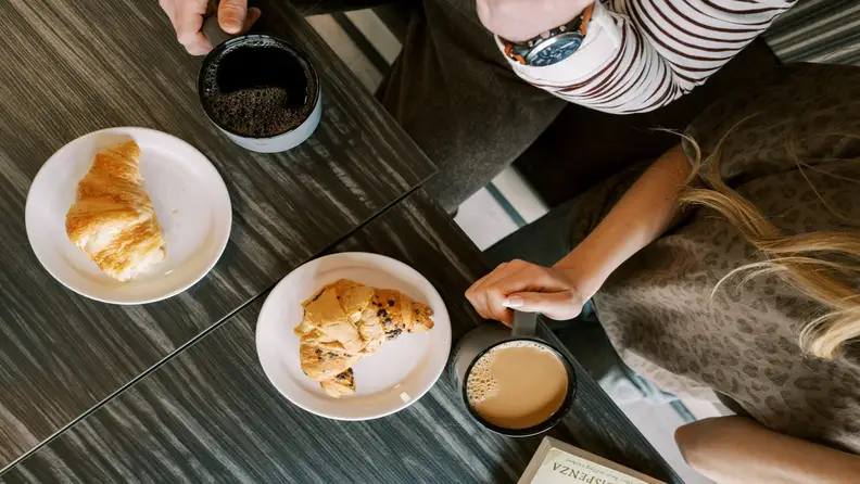 Overhead view of two people with coffee and croissants at a table