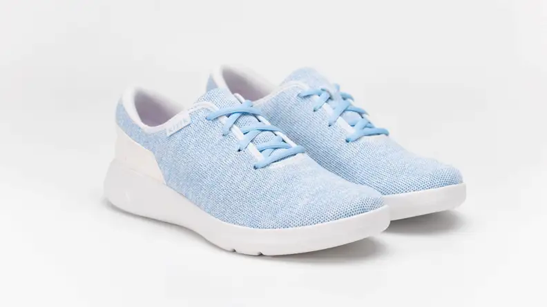 A pair of baby blue Kizik shoes against a gray background