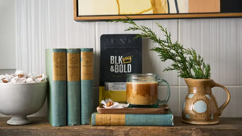 Coffee bag and iced coffee mug styled with books and plant