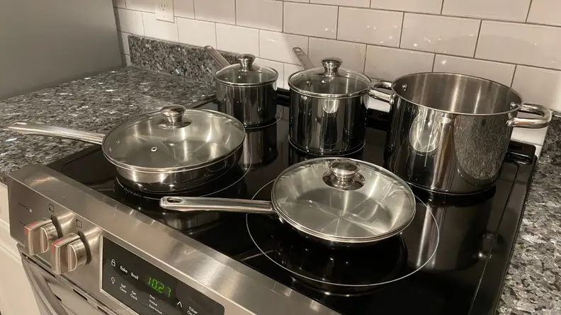 Stainless steel pots and pans resting on an electric cooktop.