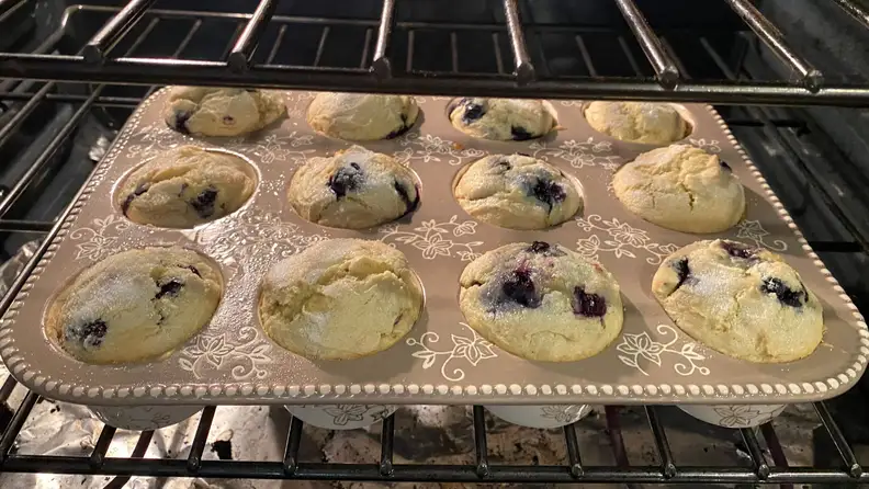 Temp-tations muffin pan filled with blueberry muffins, inside an oven.