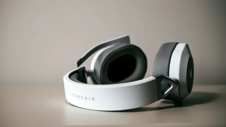 A white pair of headphones sits on a surface.
