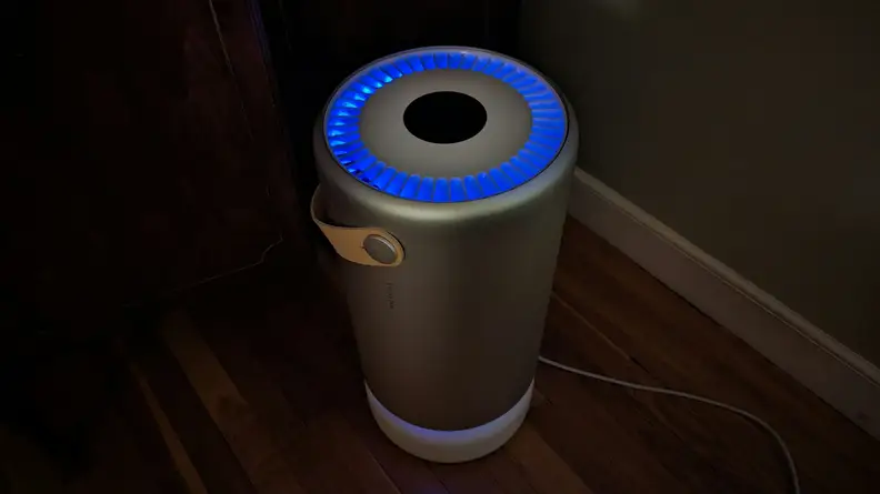 The Molekule air purifier glows with a blue UV light ring around the top.