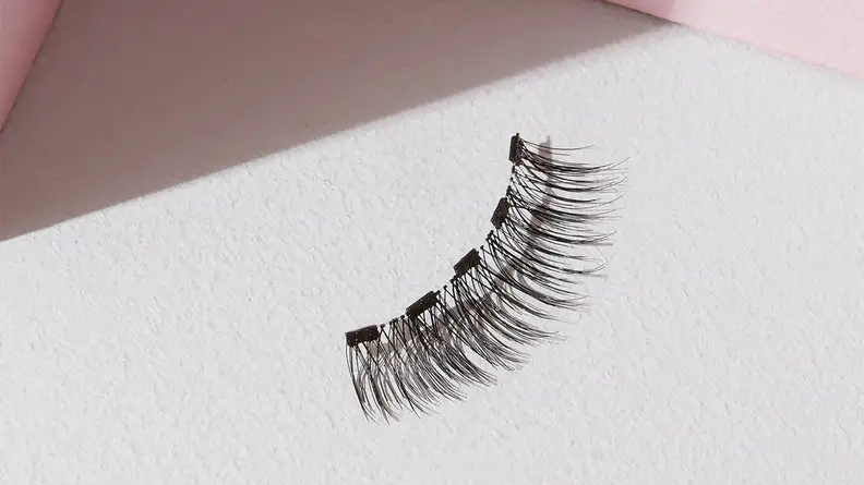 A single magnetic eyelash from the Lola’s Lashes Rose Quartz Magnetic Eyelashes and Eyeliner Kit on a white background.