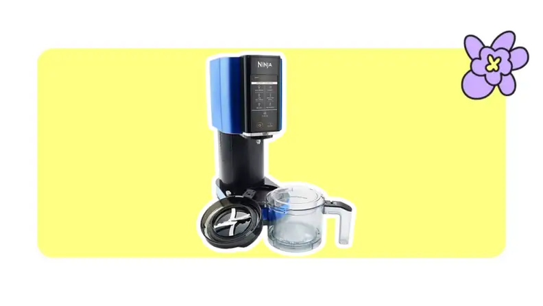A Ninja CREAMi ice cream and frozen treat maker with a sleek black and blue design is displayed on a bright yellow background, alongside its transparent pint container and lid, with a purple cartoon flower in the top right corner.