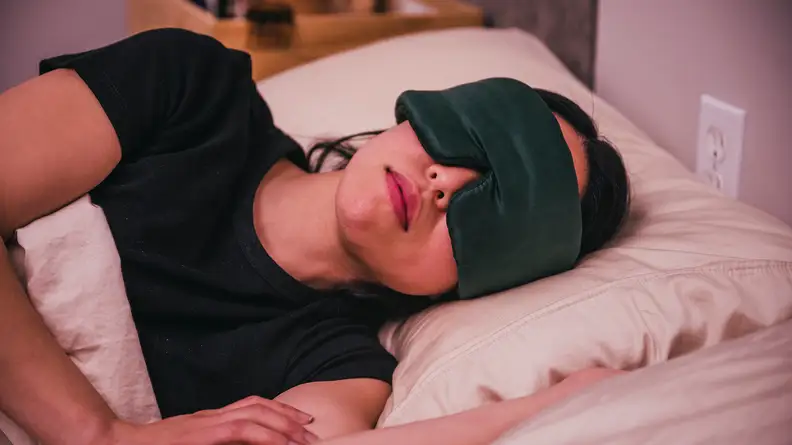 Person sleeping in bed wears a silk sleep mask