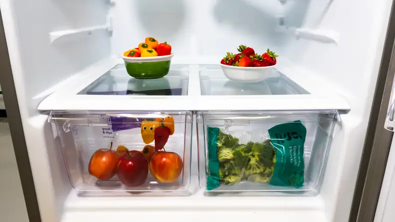 A close-up of the Whirlpool WRT518SZFM top-freezer fridge's crisper drawers, filled with fresh veggies for scale.