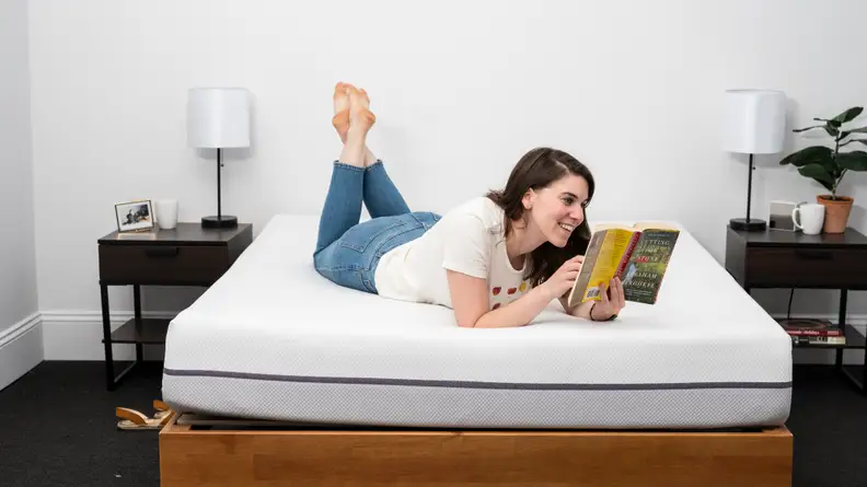 a person lies on their stomach reading on the purple mattress