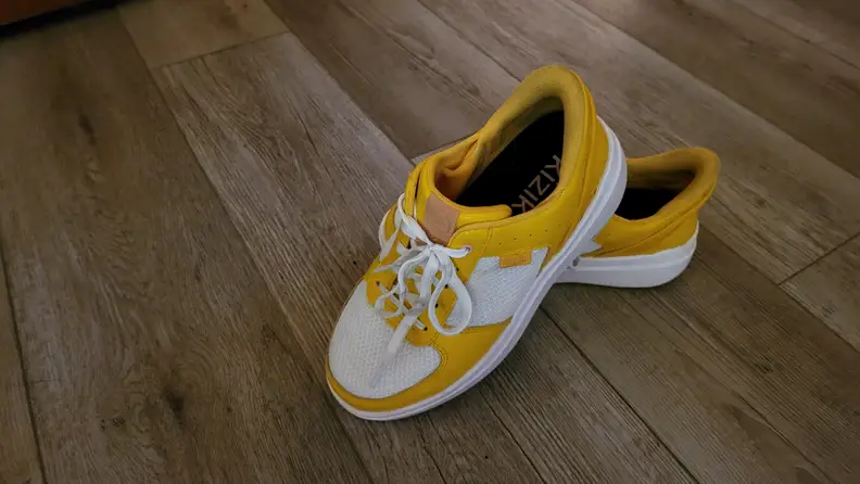 A yellow pair of Kizik Brisbane shoes against a wood floor