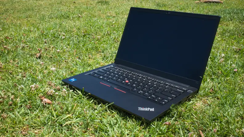 An open laptop resting on a field of grass