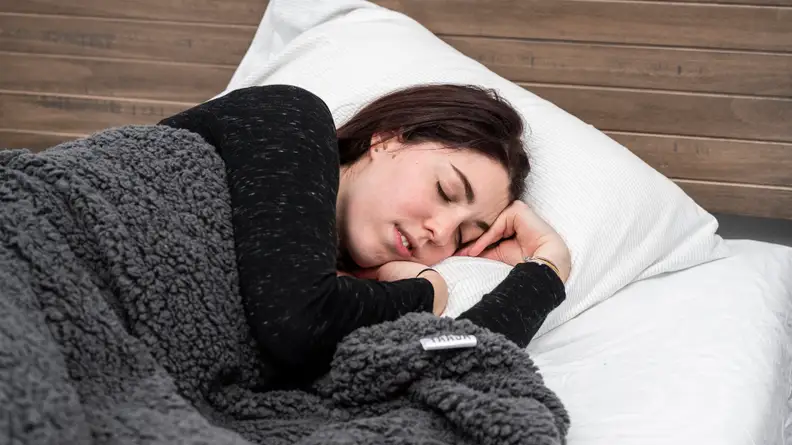 a person sleeps under the yaasa weighted blanket