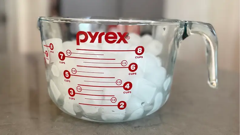 Clear Pyrex measuring cup filled with bullet-shaped ice.
