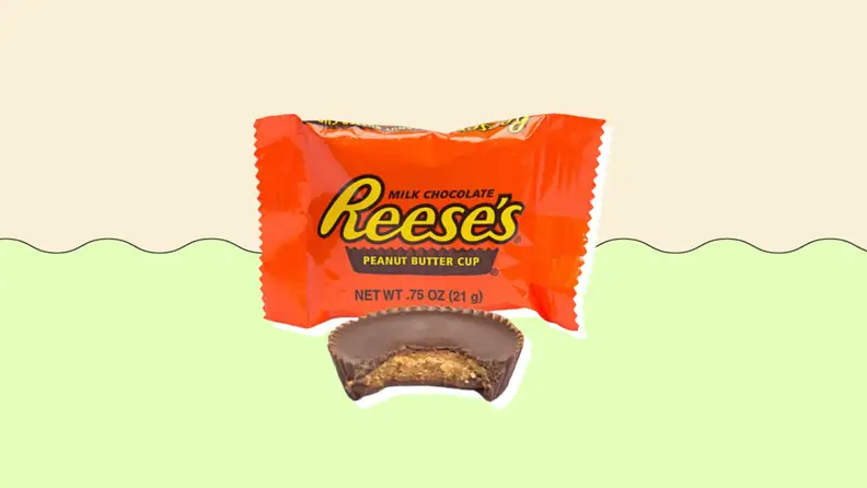 A bitten Reese's cup in front of its accompanying package.