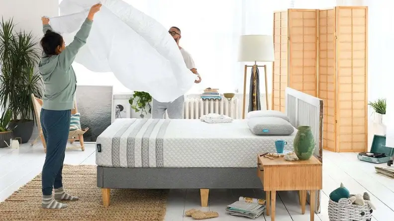A couple gets ready to put a sheet on their new Leesa hybrid mattress.