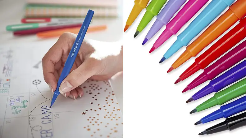On left, hand holding blue felt tip pin is writing on a calendar. On right, an array of multi-colored felt-tip pens all lined up in a curved half-circle.