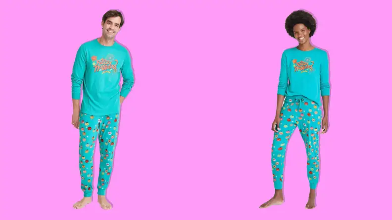A woman and a man wearing Wondershop Feliz Navidad matching pajama set on pink background.