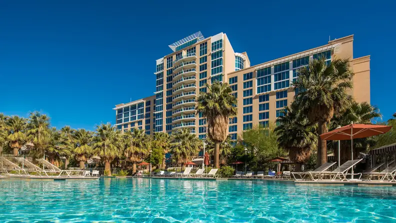 Agua Caliente Rancho Mirage Resort in California featuring a large outdoor pool surrounded by palm trees and lounge chairs beneath a clear blue sky.